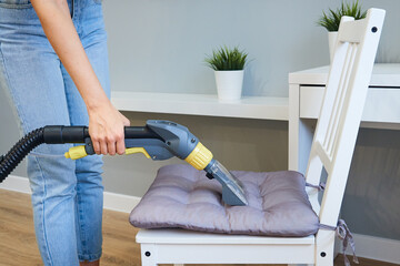 Close-up woman cleaner cleaning furniture with a vacuum cleaner