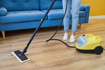 Cropped image of woman cleaning room floor using vacuum cleaner