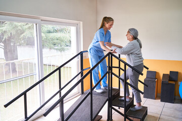 Female therapist assisting elderly woman in movement therapy