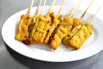 Grilled pork satay on white plate
