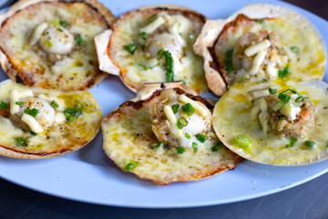 Grilled scallops shell with butter and garlic on white plate