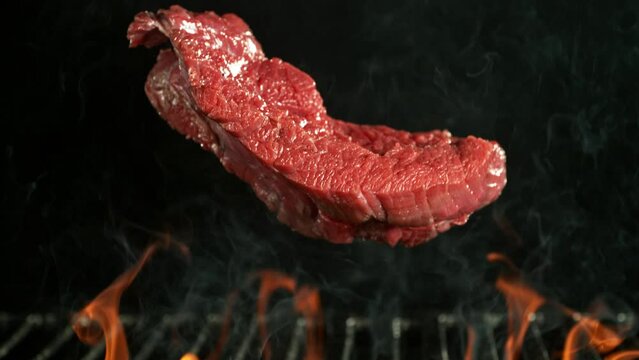 Super Slow Motion of Beef Steak Falling on Grill With Fire on Black Background. Filmed on High Speed Cinema Camera, 1000 fps, Placed on High Speed Cine Bot, Following the Target.