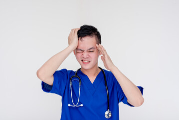 A disappointed and frustrated young medical student or intern or nurse posing with his hand on his temple and looking troubled. Isolated on a white background.