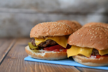 Several homemade burgers on plastic cutting board and wooden background