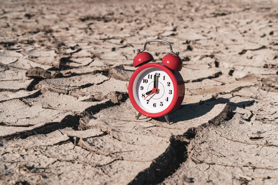 Alarm clock on arid cracked soil