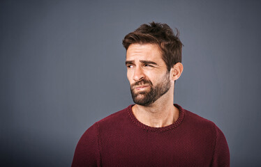 Obraz premium Doubt, thinking and face of unsure man in studio with worry, uncertain and thoughtful on gray background. Confused, mockup space and isolated male person skeptical for decision, choice and question