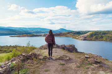 Obraz premium Traveler woman walking above a blue lake with stunning panoramic view .Traveling in the nature in Bulgaria . Pchelina Lake