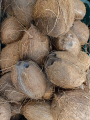 many fibrous coconut pods in a street shop. Top view. Fresh tropical fruits and vegetables copy space background