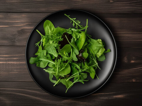 Green salad with fresh leaves in black plate on wooden table, generated ai