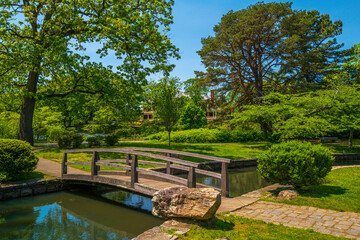 Fototapeta na wymiar Japanese Garden at Roger Williams Park, Providence, Rhode Island, a footbridge over the pond, and green trees on the island