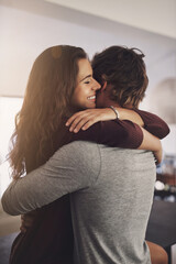 Happy woman, man and hug in home for love, care and quality time together with commitment to relationship. Young couple, hugging and anniversary of lovers, smile and happiness of loyalty to partner
