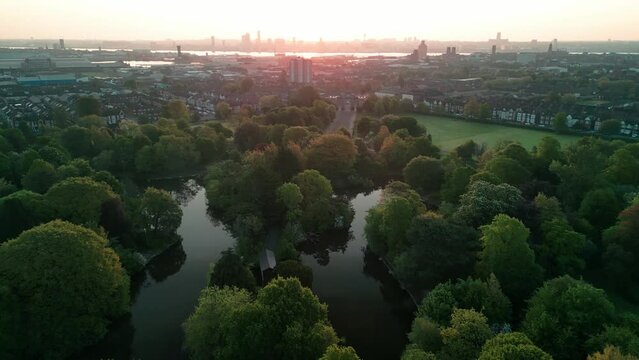 Birkenhead Park, upon which Central Park NY is based - Aerial drone at dawn, Liverpool skyline slow approach over lake - May 23
