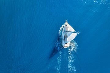 Wave and sail yacht on the sea as a background. .Sea and waves from top view. Blue water background from top view. Top view from drone. Summertime vacation. Travel image - obrazy, fototapety, plakaty