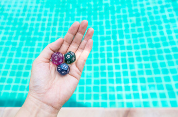 Dice divination in girl hand over blurred swimming pool background, astrological dices fortune telling divination tools, second house with Aries zodiac sign and north node sign