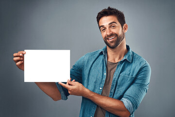 Happy man, billboard and mockup for advertising, marketing or branding against a grey studio background. Portrait of male person holding rectangle poster, placard or board of empty sign for message