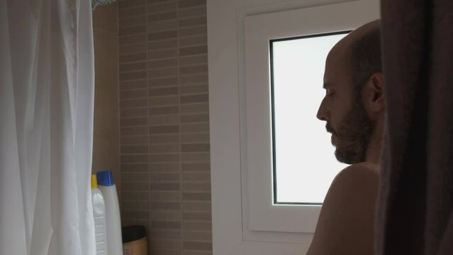 Caucasian young man taking a shower in the sink at home, enjoying a bath under the water drops. backlit view
