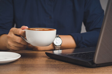 Man in a shirt holding a cup of coffee while sitting at the table