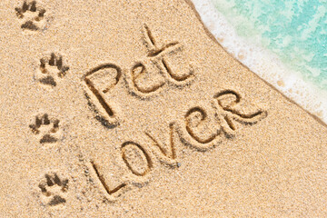 Fototapeta na wymiar Pet lover text on beach. Paws prints shape and footprints of animals. Travel and beach vacation with dog or cat concept photo