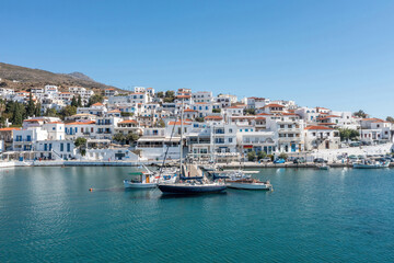 Fototapeta na wymiar Andros island, Batsi village, Cyclades Greece. View of seafront building, cafe, port, sea, sky.