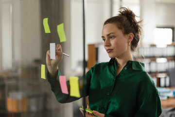 Young woman taking notes in her office.