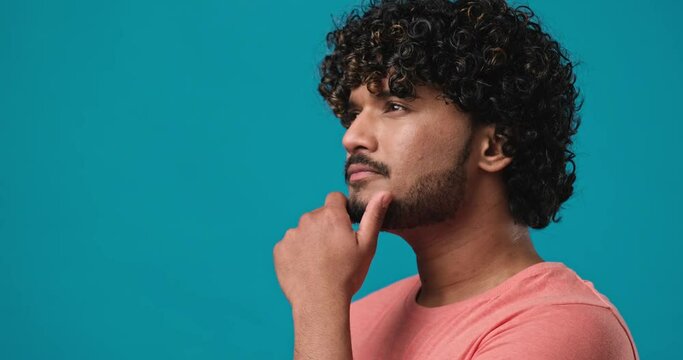 Serious pensive thinkful indian man standing isolated over blue studio background