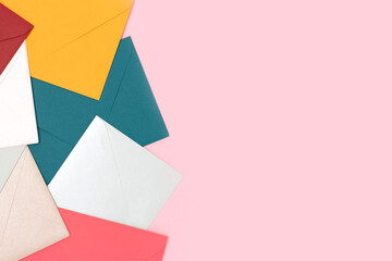 Multicolored envelopes scattered on a pink background. Creative concept with place for your design.