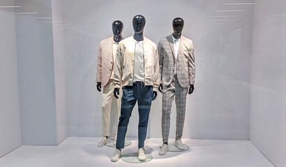 Three male mannequins in store window show fashion collection for men. Dummies in shop