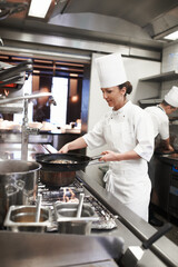 Chef, woman and frying pan in restaurant kitchen, catering service and prepare food for fine...