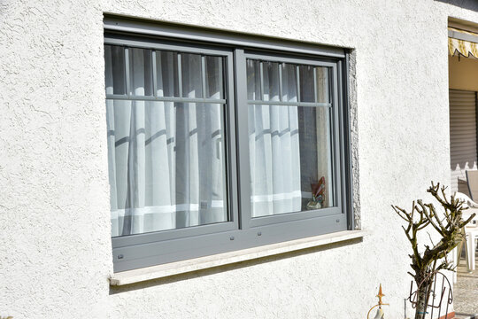 Moderne Fenster in einer gemauerten, verputzten und gestrichenen Fassade eines modernen Wohnhauses