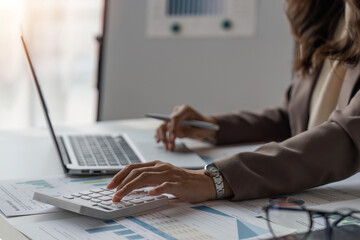 business woman or accountant who are using a calculator to calculate business data Accounting documents and laptop computer at the office business idea