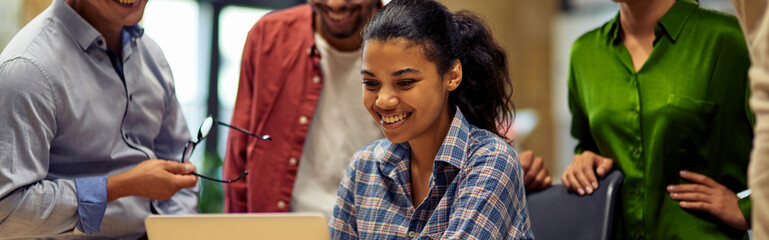Group of happy multiracial business people looking at laptop screen, discussing project results and...