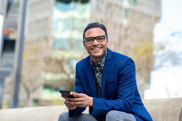 Good looking black businessman sitting outside with cell phone