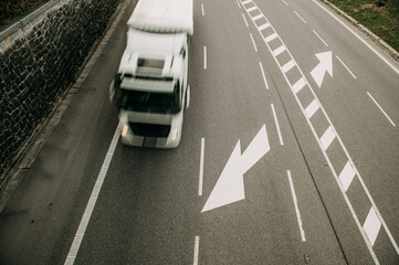 aerial image of a road with an arrow symbol and a truck, the vehicle is blurred due to movement
