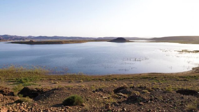 Lake El Mansour Eddahbi dam water reservoir in Ouarzazate, Morocco. Low-level water, drought, volcanic mountains, global warming, 4k footage. 