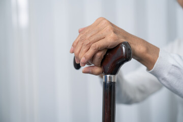 physical therapy elderly woman on a walking wood standard cane in disability nursing rehabilitation center.
