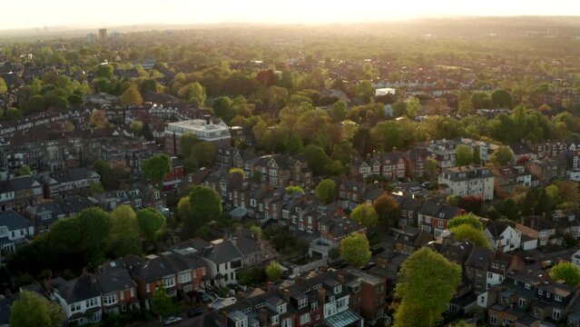 Low aerial shot over North London suburban row houses backlit at sunset