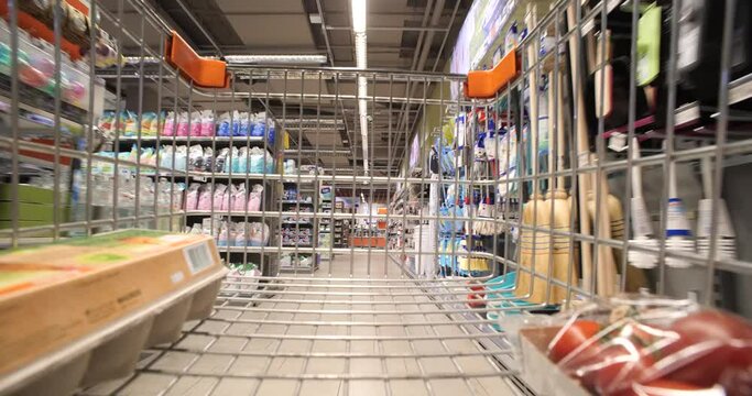 Shopping cart being pushed inside generic grocery store isles. Ultra-wide-angle view, no people, real time