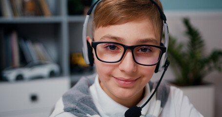 Close up portrait of teenager in headphones looking at camera with joyful smile. Cue cheerful kid posing at camera and smiling.