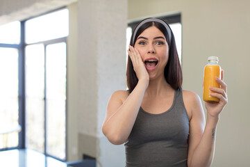 pretty young woman feeling happy and astonished at something unbelievable. orange juice concept