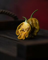 Fototapeta premium Hot mustard pepper habanero. Whole pepper and half stand on wooden surface. Sectional view. Pepper seeds. Spices. Mexican pepper. Spicy food. Close-up. Side view. Soft focus. Copy space.