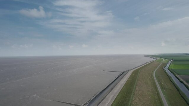 Aerial shot of a Dutch dyke between the Wadden Sea and the flat green countryside of the Netherlands