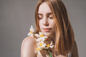 Beautiful white girl with narcissus flowers portrait in sunlight. Closeup face of young beautiful...