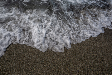 oceano de agua salada con olas, piedras y arena