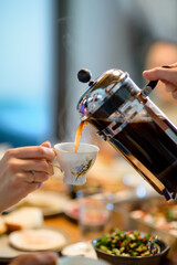 Girl pours coffee into a porcelain cup for breakfast