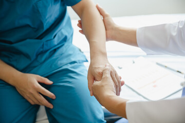 Doctor or Physiotherapist working examining treating injured arm of athlete male patient, stretching and exercise, Doing the Rehabilitation therapy pain in clinic.