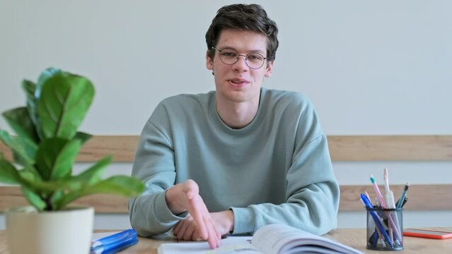 Teenage male student having video conference, talking looking at webcam