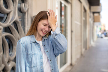 pretty young woman laughing and slapping forehead like saying d’oh! I forgot or that was a stupid mistake