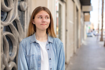 pretty young woman wondering, thinking happy thoughts and ideas, daydreaming, looking to copy space on side