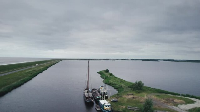 Aerial over a lake and boats along a Dutch dyke between the Wadden Sea and the flat green countryside of the Netherlands
