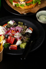 Close up of Greek salad on black plate fast food